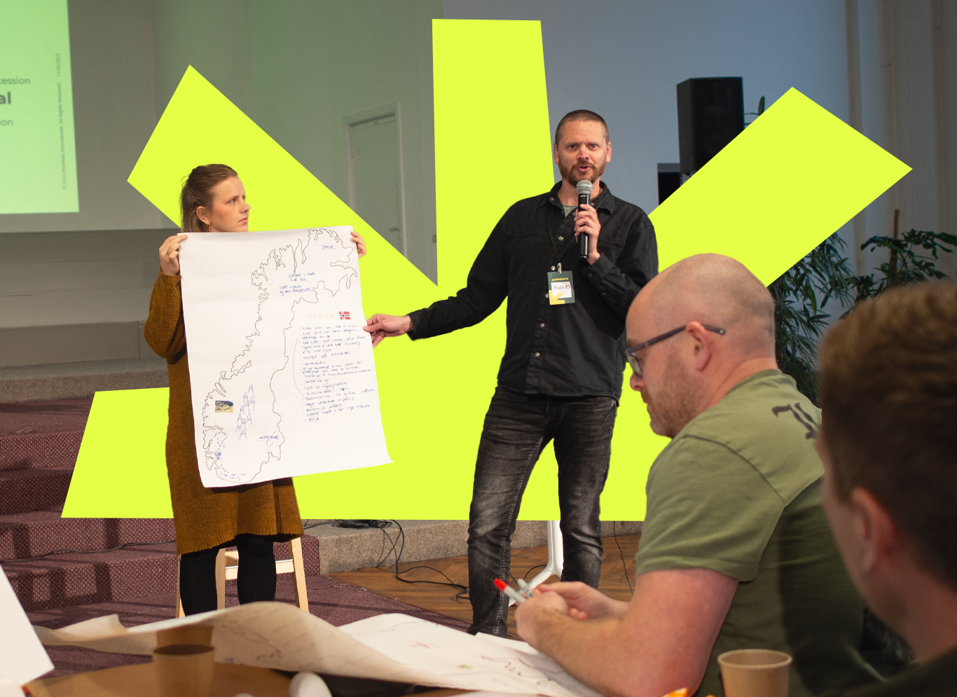 Man with microphone pointing to a whiteboard at a training event